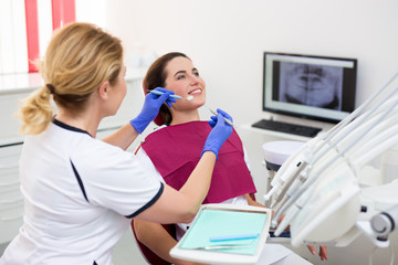dentist working with happy female patient at dental clinic