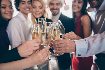 Cropped photo of fellows group party people celebrating x-mas clinking wineglasses sparkling wine wear formalwear santa hats restaurant indoors