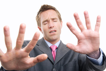 Lost businessman with eyes closed holding hands out to feel his way against a white background