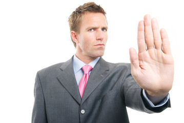 Frowning businessman holding out a warning gesture hand against a white background