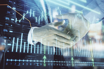 Double exposure of financial chart on cityscape background with two businessmen handshake. Concept...