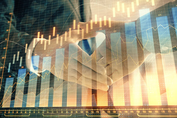 Double exposure of financial graph on cityscape background with two businessman handshake. Concept of stock market deal