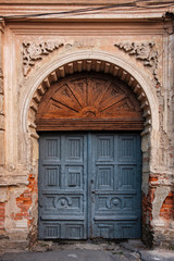 Fototapeta na wymiar Old arched wooden door in ornate wall