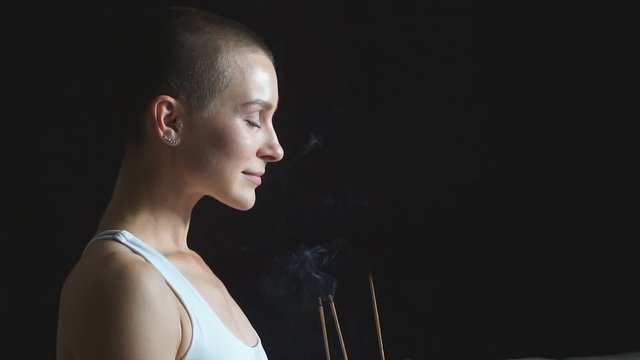 Attractive woman in white clothes inhales smoke from candle. Healthy lifestyle