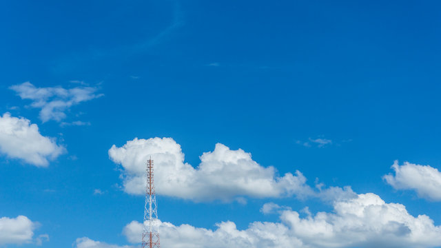 Telecommunication telephone signal transmission tower with cloud and blue sky background.