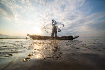 Picture of Asian fishermen on a wooden boat Thai fishermen catch fresh water fish in the natural...