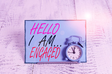 Conceptual hand writing showing Hello I Am Engaged. Concept meaning He gave the ring We are going to get married Wedding Alarm clock tilted above buffer wire in front of notepaper