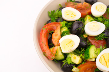 Mix of fresh vegetables. Salad with quail eggs tomato cucumber olive. plate with egg and vegetable salad on white