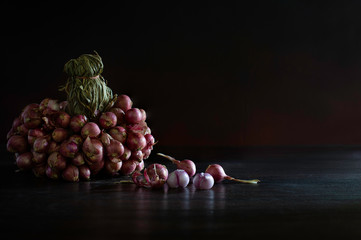 Bunch of shallot and some shallots fall off and peeled on dark wooden background which has dim light