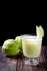 Guava juice in glass and fresh guava on wooden background, giving a fresh feeling.