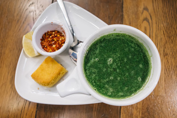 Turkish traditional nettle soup on wooden and white background.Soup with fresh nettles