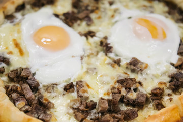 Turkish traditional round pita bread (Turkish pide) with cheese, eggs and meat