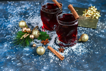 Christmas red wine mulled wine with spices and on a dark background. Around the white snow. New Year. Christmas decorations, cinnamon sticks. Copy space. 