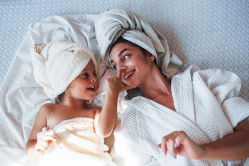 Top view. Using creme. Young mother with her daugher have beauty day indoors in white room