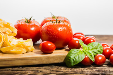 TOMATOES ON A BOARD WITH BASIL AND SPICES