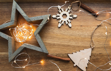Festive Christmas or New Year flat lay with wooden fir toys and festoon on a wooden background.