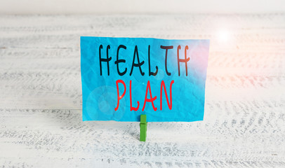 Word writing text Health Plan. Business photo showcasing entity that provides coverage of designated health services Green clothespin white wood background colored paper reminder office supply