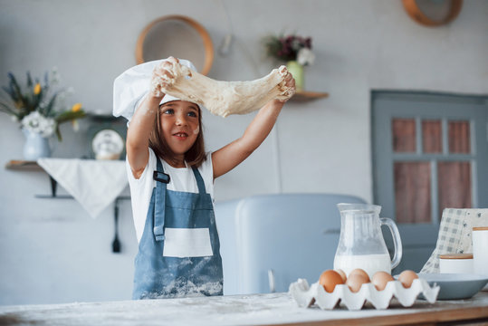 Cute Kid In White Chef Uniform Preparing Food On The Kitchen