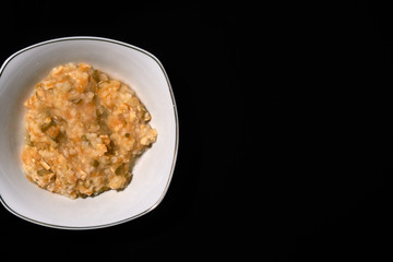 baby food on bowl isolated black background, flat lay top view
