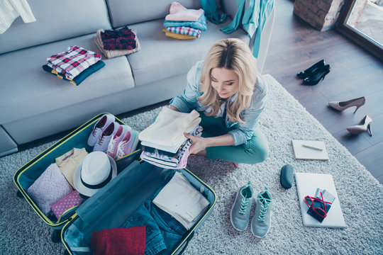 Above high angle view portrait of nice attractive pretty cheery wavy-haired girl folding organizing tidy clean fresh clothes for relocation flight at modern industrial loft brick style interior