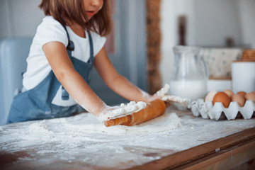 Obraz na płótnie Canvas Close up view. Cute kid in white chef uniform preparing food on the kitchen