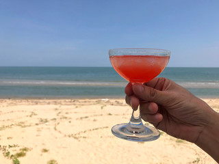 Relaxing in vacation at beautiful sunny beach with delicious juice in the woman hand.