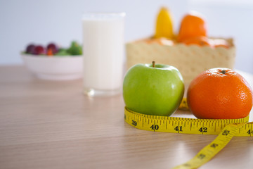 Tape measure around the green apple. Next there are milk and vegetable salad on the wooden table. Eating for good health and weight loss. Diet concept