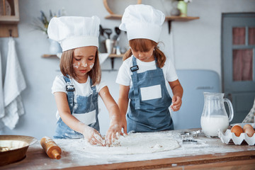 Concentrating at cooking. Family kids in white chef uniform preparing food on the kitchen