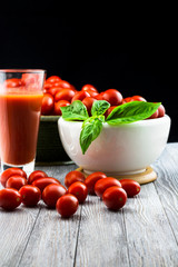 CHERY TOMATOES ON BLACK BACKGROUND WITH BASIL AND JUICE WITH SELECTIVE FOCUS