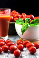CHERY TOMATOES ON BLACK BACKGROUND WITH BASIL AND JUICE WITH SELECTIVE FOCUS