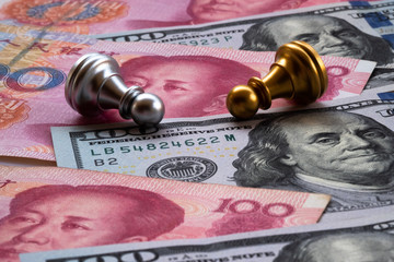 Chess game, two pawns fall down on Chinese yuan and US dollar background. Trade war concept. Conflict between two big countries, USA and China concept.