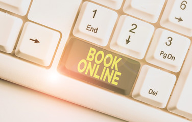 Writing note showing Book Online. Business concept for booklike form that is only available to read on the Internet White pc keyboard with note paper above the white background