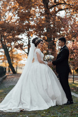 Young wedding couple enjoying romantic moments. Young lovers are happy to walk. Elegant bride and groom posing together outdoors on a wedding day. Portrait of an attractive groom and bride  in autumn.