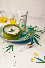 Cosmetics CBD oil on a turquoise plate on a light marble background. Copy space, mockup.