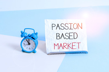 Conceptual hand writing showing Passion Based Market. Concept meaning Emotional Sales Channel a Personalize centric Strategy Alarm clock beside a Paper sheet placed on pastel backdrop