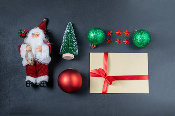 Christmas composition with Santa Claus, shiny green and red Christmas balls, spruce, stars and a gift on a dark background. Top view, flat lay