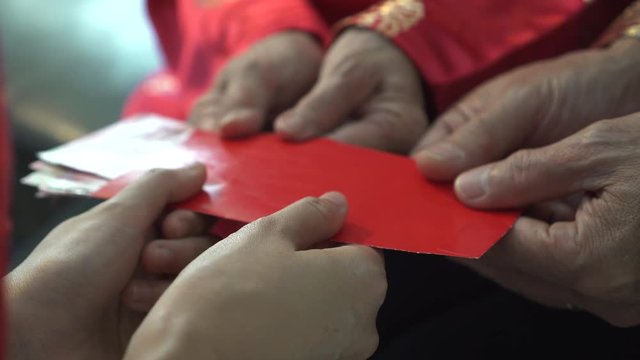 Hands parents giving red envelop and money to children for Chinese New Year close up