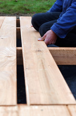Handy carpenter installing wooden planks during flooring works outside the new house. Czech republic, Europe.