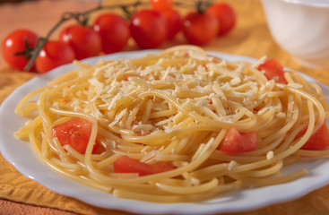 Italian Parmesan pasta on a white plate, sprinkled with spices and decorated with chili tomatoes