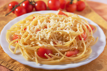 Italian Parmesan pasta on a white plate, sprinkled with spices and decorated with chili tomatoes