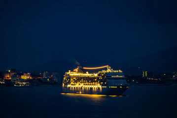 Big cruise ship with festive night lights stopped for the night in the bay near the sea port of...