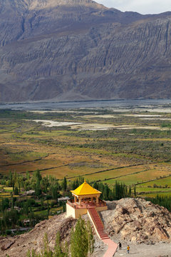 a view of golden colored temple from diskit monastery, ladakh against mountain landscape