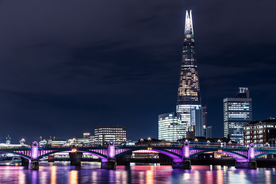 Modern London city skyline on River Thames with shard building and illuminated river lights