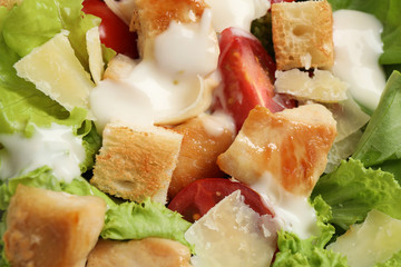 Tasty Caesar salad with chicken as background, closeup