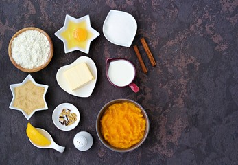Ingredients for making American pumpkin pie: pumpkin puree, flour, butter, spices, salt, cream, brown and white sugar, egg, lemon. Thanksgiving dessert recipe. Top view, copy space.