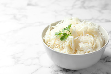 Tasty fermented cabbage on white marble table, closeup
