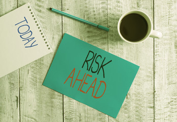 Writing note showing Risk Ahead. Business concept for A probability or threat of damage, injury, liability, loss Stationary placed next to a cup of black coffee above the wooden table
