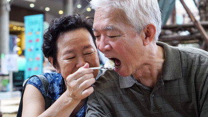 Loving Asian elder couple feeding ice crean happy dating outdoor