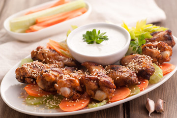 Hot buffalo chicken wings with blue cheese sauce and fresh vegetables.