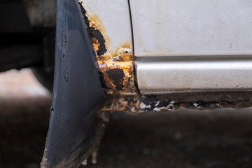 Hard corrosion and rust on the body and doors of the car white.